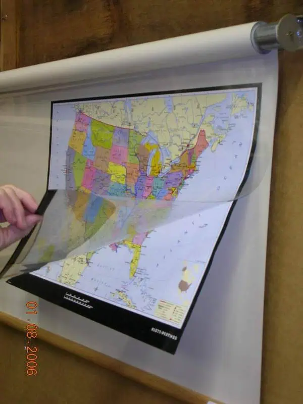 Map shop's large, colorful road and state map being unrolled on a wall display for detailed navigation and travel planning.