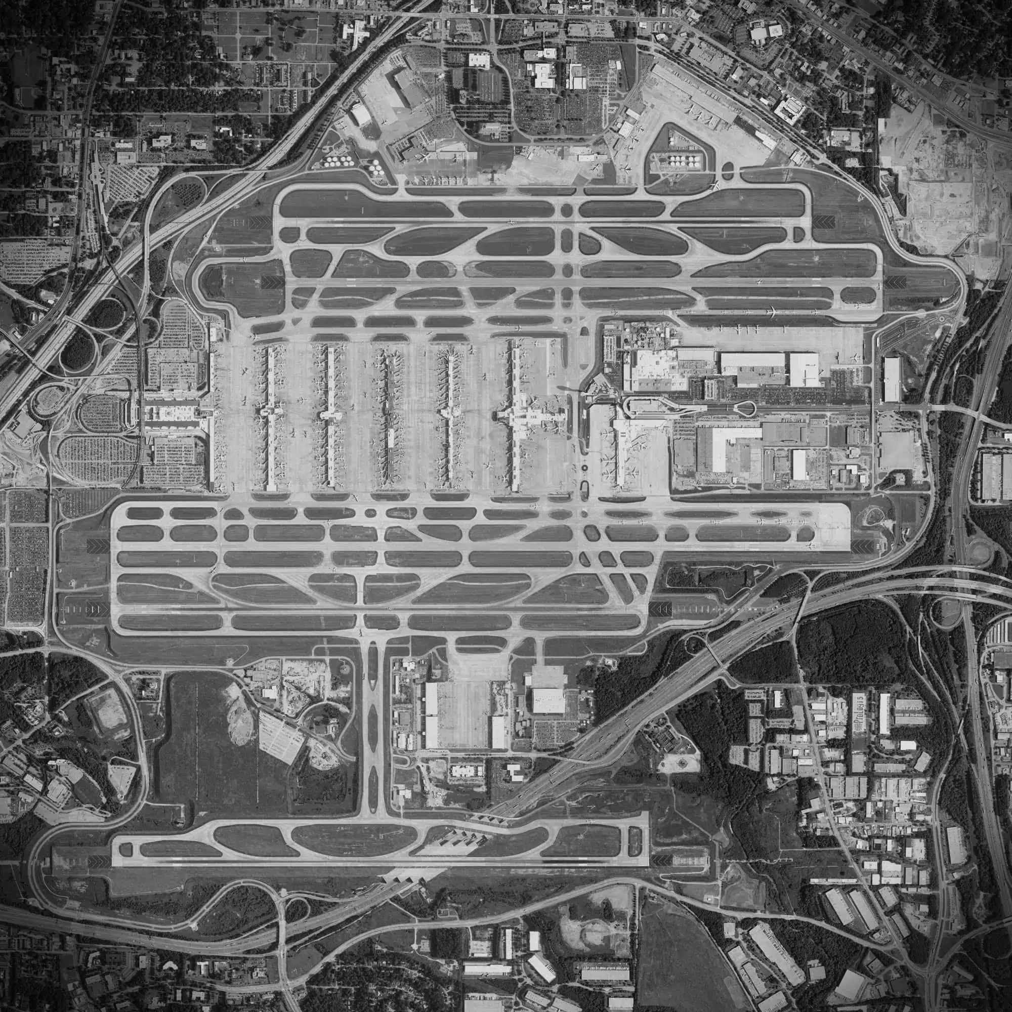 Aerial view of Denver International Airport showing extensive runways, taxiways, and surrounding infrastructure in black and white.