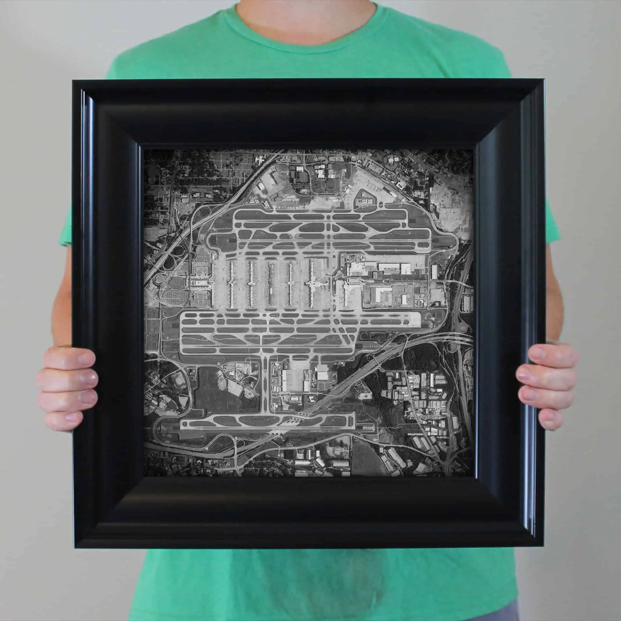 Detailed aerial view of a large airport, including runways, taxiways, and surrounding infrastructure, displayed in a sleek black frame for travel maps and navigation reference.
