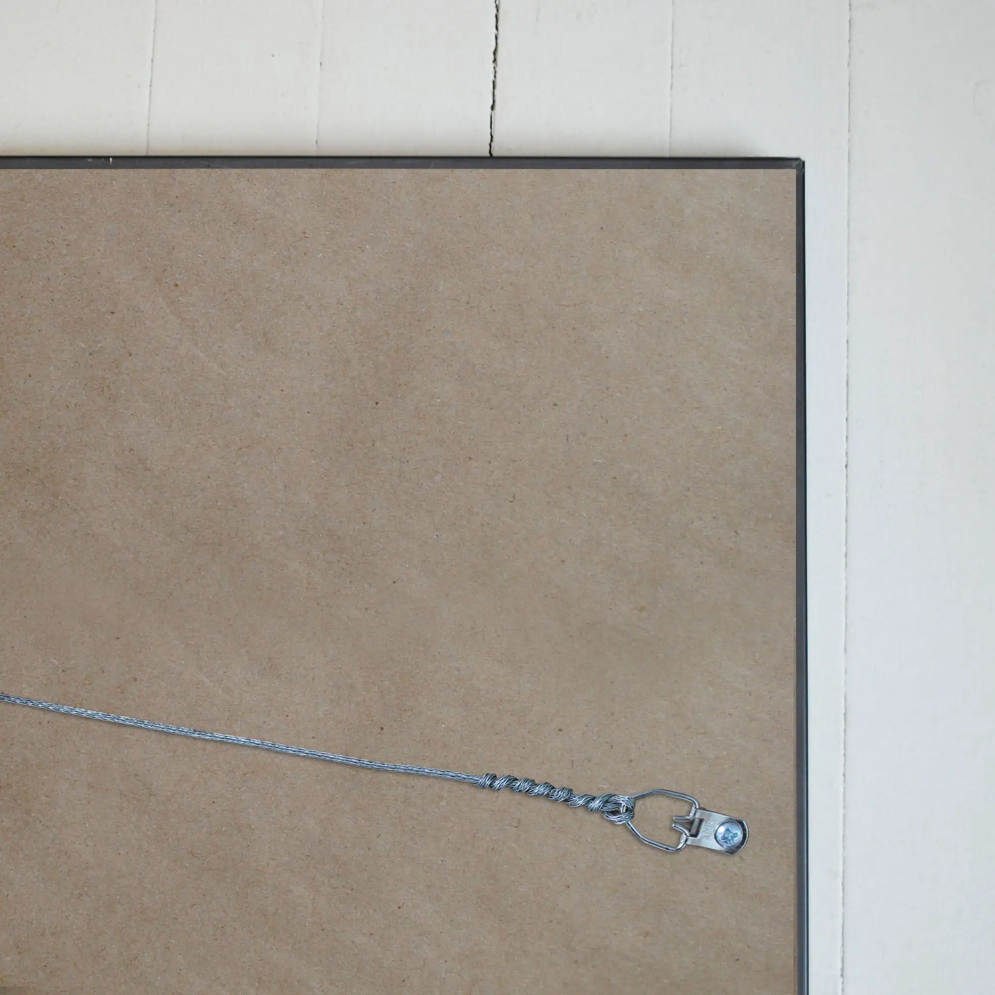 Wire jewelry display stand with a heart-shaped clasp and screw detail on a framed corkboard, ideal for showcasing maps or accessories in a modern, minimalistic setting.