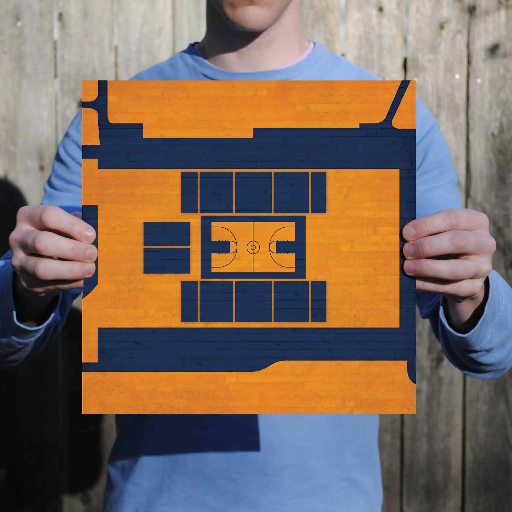 Colorful wooden basketball court miniature map held by a person outdoors against a wooden fence.