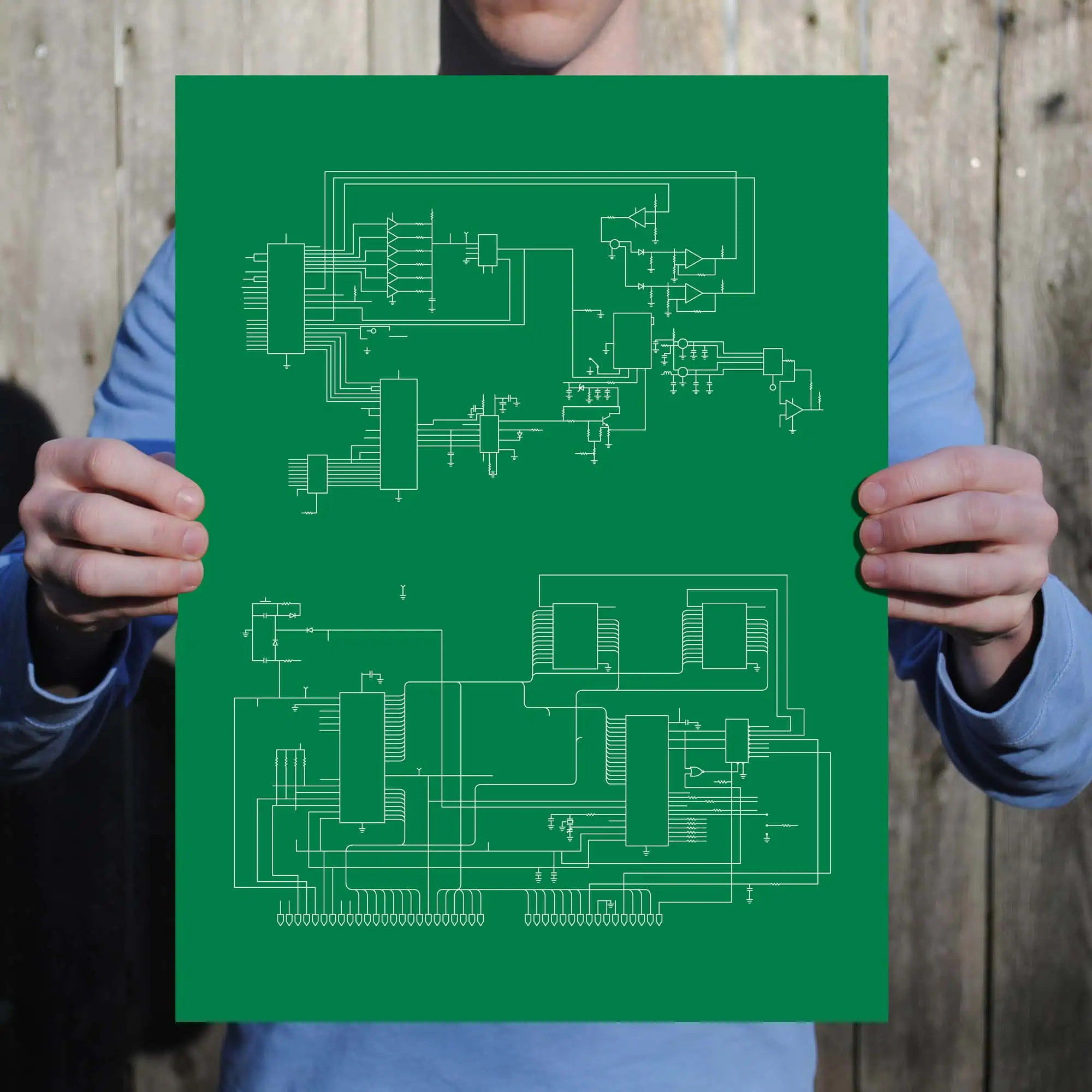 Circuit diagram on a green background held by a person in a blue shirt, representing electronic schematics and technical drawings, ideal for electronics and engineering enthusiasts.