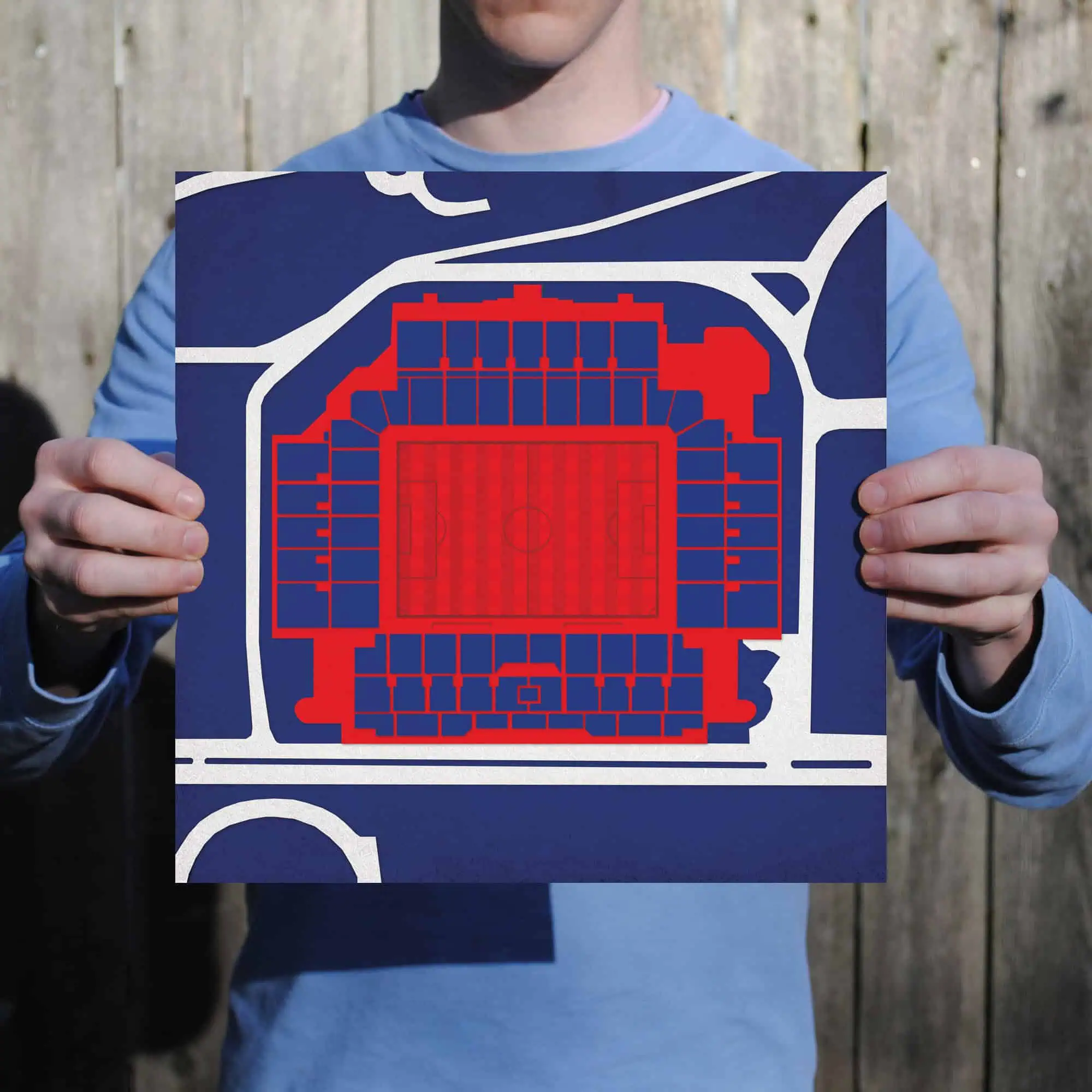 A person holding a seating chart or stadium map printed on paper, showing a detailed layout of a sports arena with sections marked in red and blue, for event seating and venue navigation.