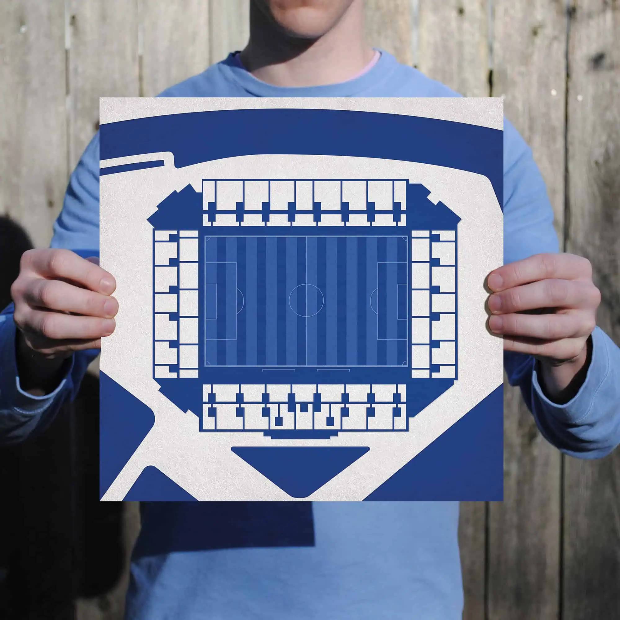 A person holding a blueprint or map of a football stadium, highlighting stadium seating and layout details, perfect for sports venue maps, stadium seating charts, and sporting event planning.