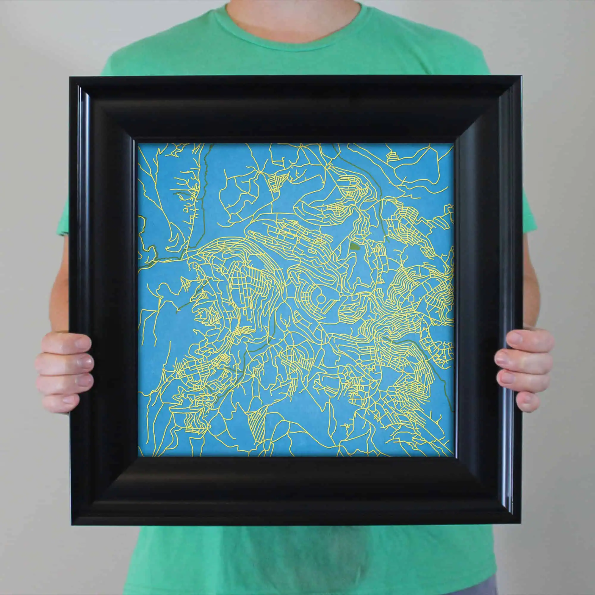 Detailed map artwork featuring vibrant yellow outlines of city streets on a bright blue background, framed for wall display, emphasizing urban navigation and cartography.