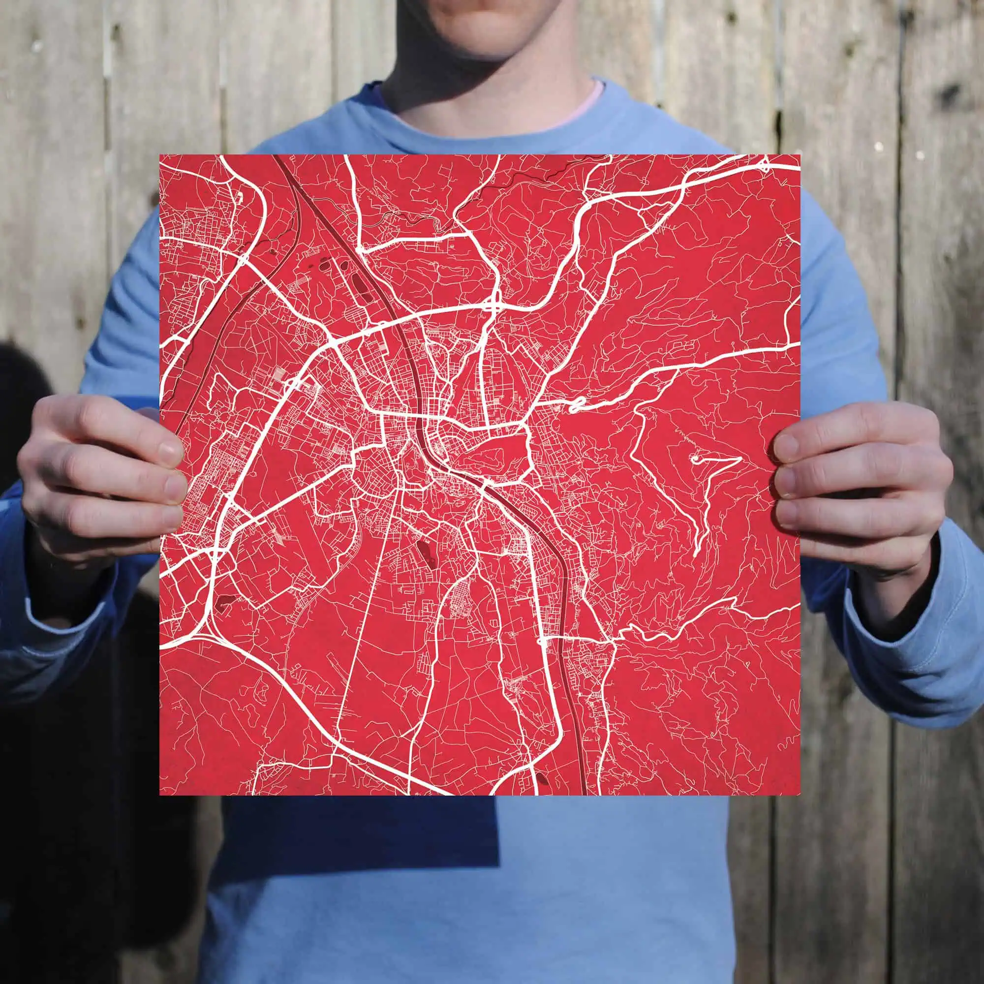 Map of city streets with detailed road network and urban layout, held by a person in a blue jacket. Perfect for travel planning, navigation, and digital map solutions.