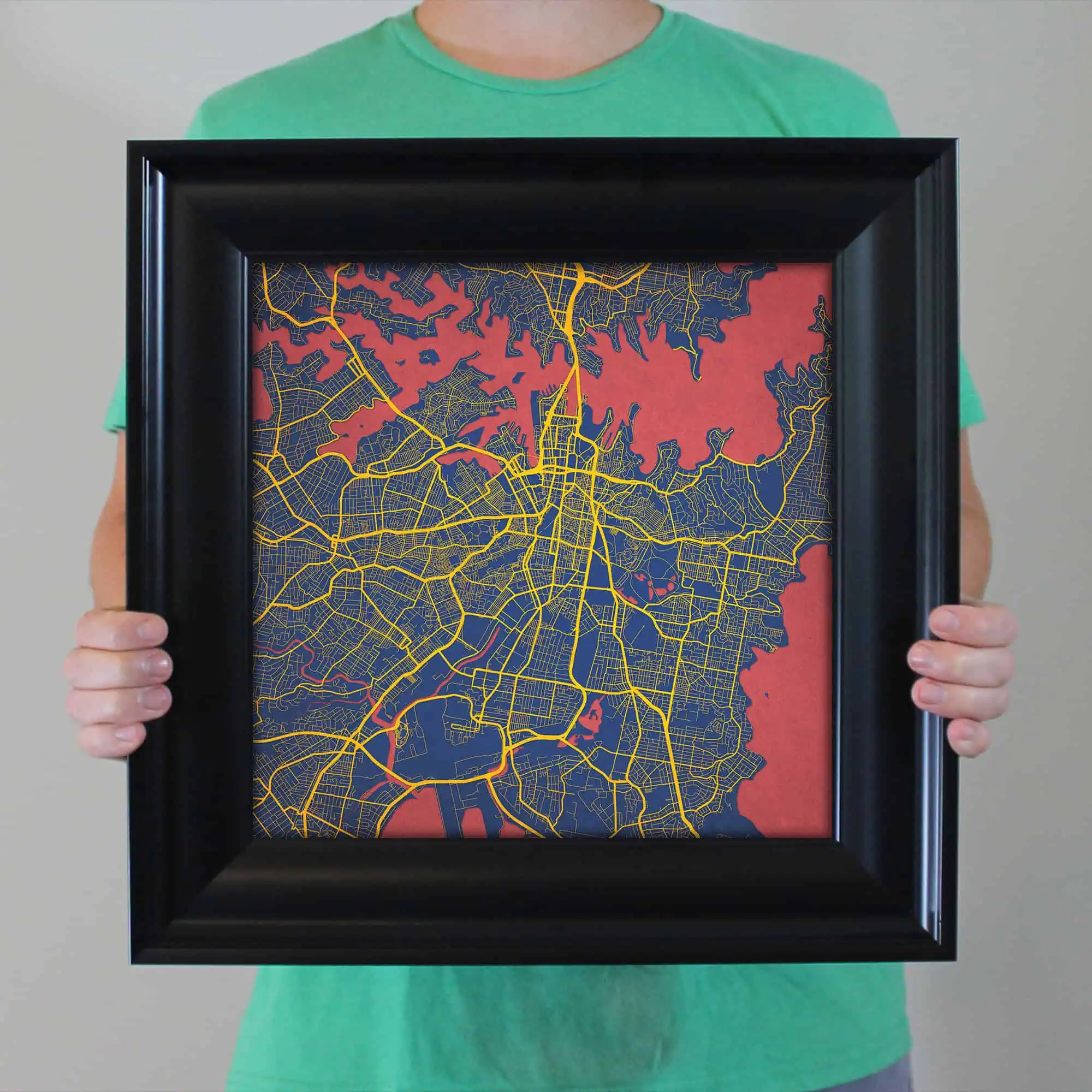Detailed map print of a city with vibrant yellow streets on a dark background, framed and held by a person in a green shirt. Perfect for wall decor, city map enthusiasts, and travel lovers.