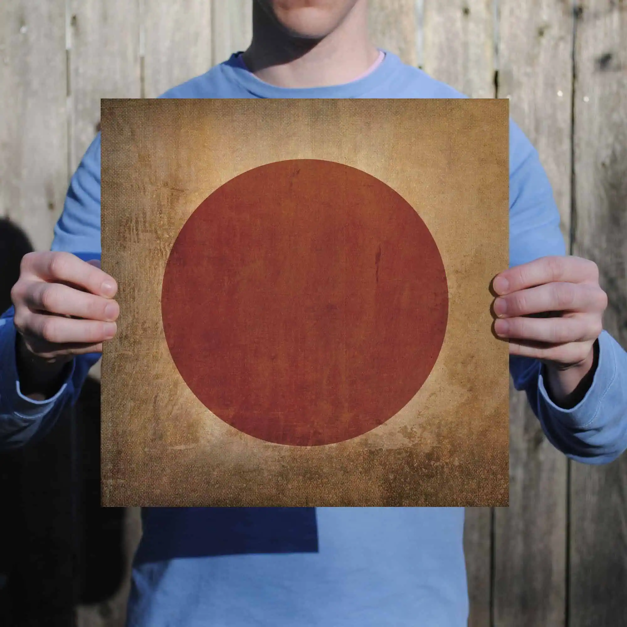 Red circle illustration printed on vintage textured background, held by person in casual clothing, emphasizing Japanese flag symbolism and cultural representation.