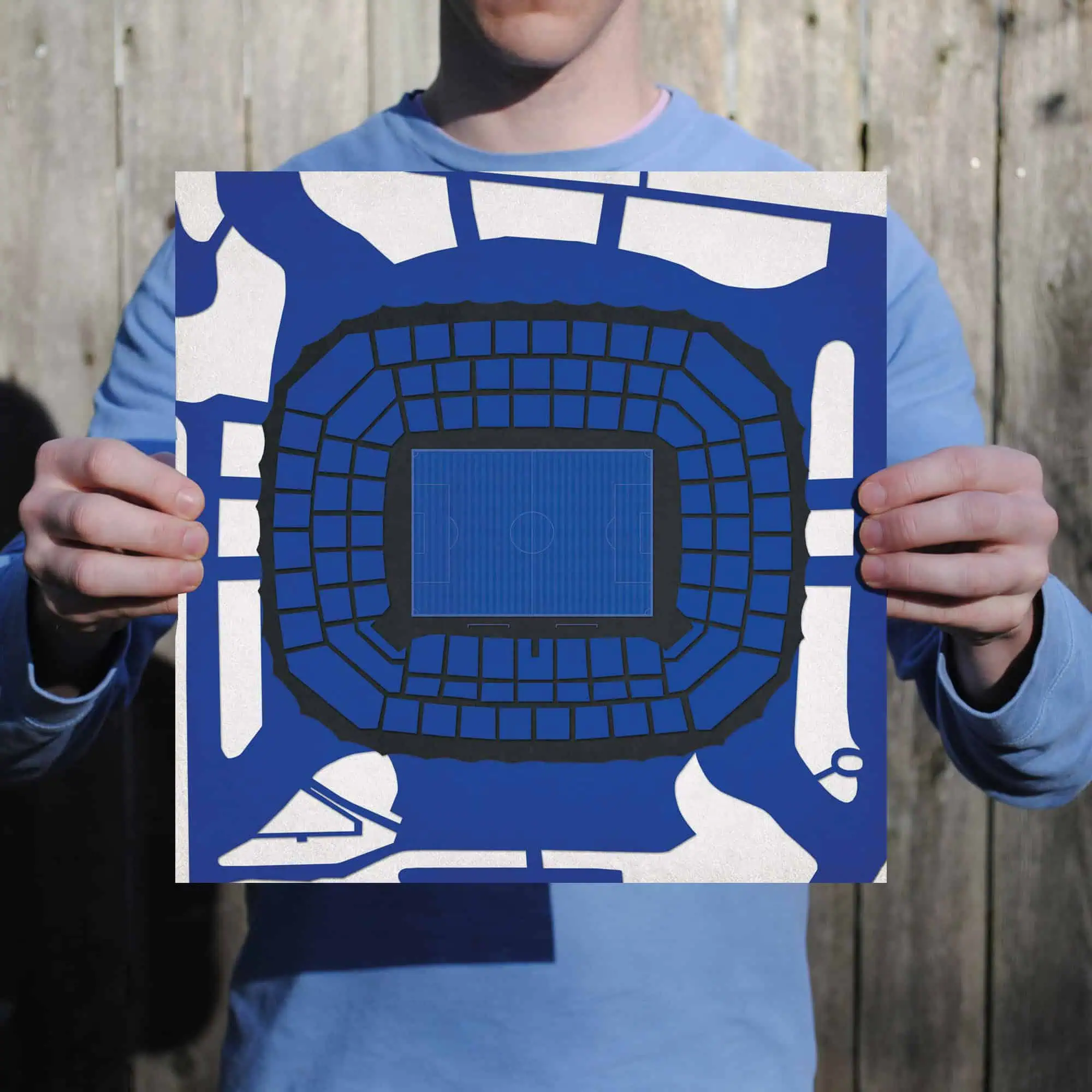 Blue stadium map mockup held by a person outdoors, showcasing seating arrangement and field layout, ideal for sports venue planning and event map design.