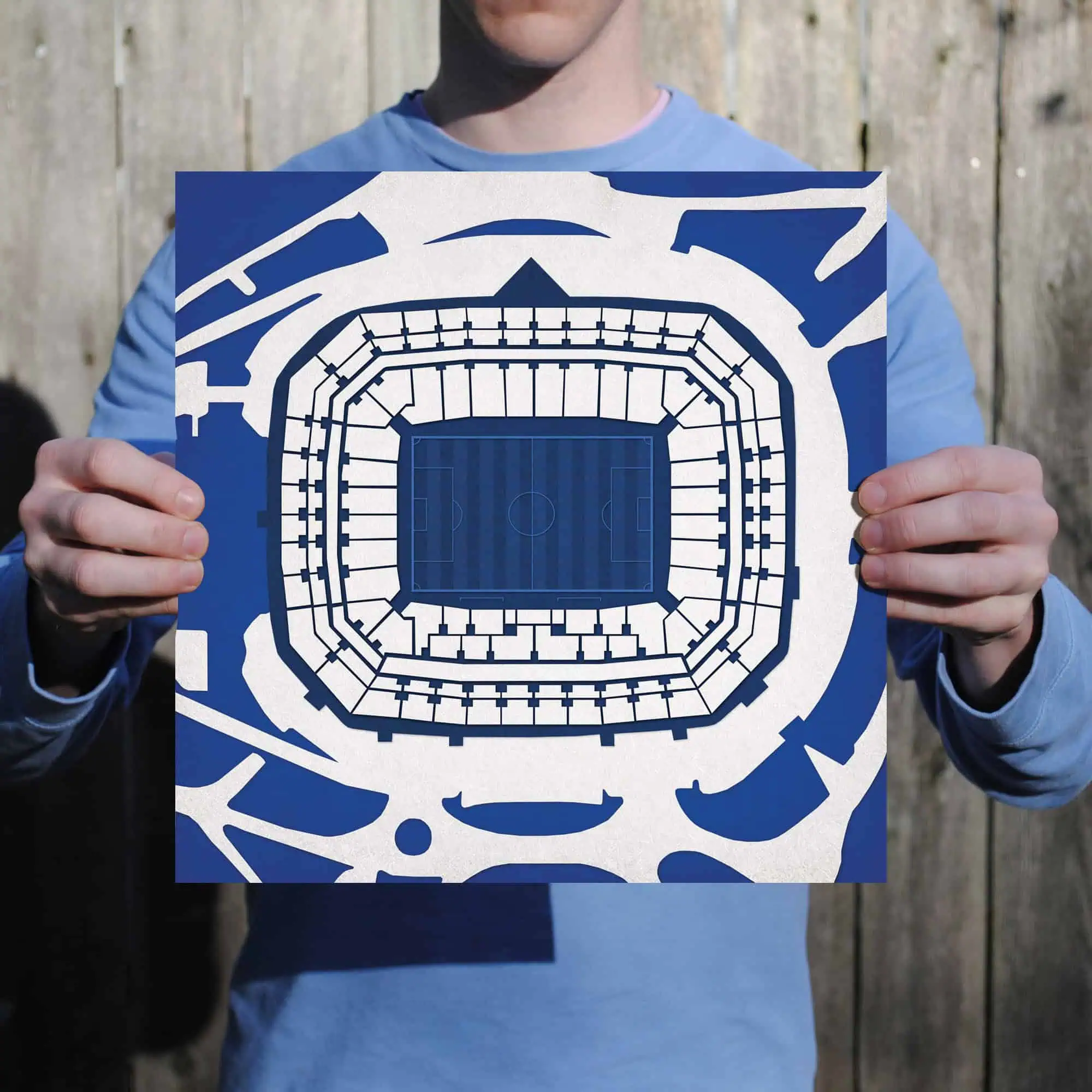 A person holding a blueprint of a stadium seating plan with a soccer field in the center, illustrating detailed stadium layout and seating arrangement for sporting events.