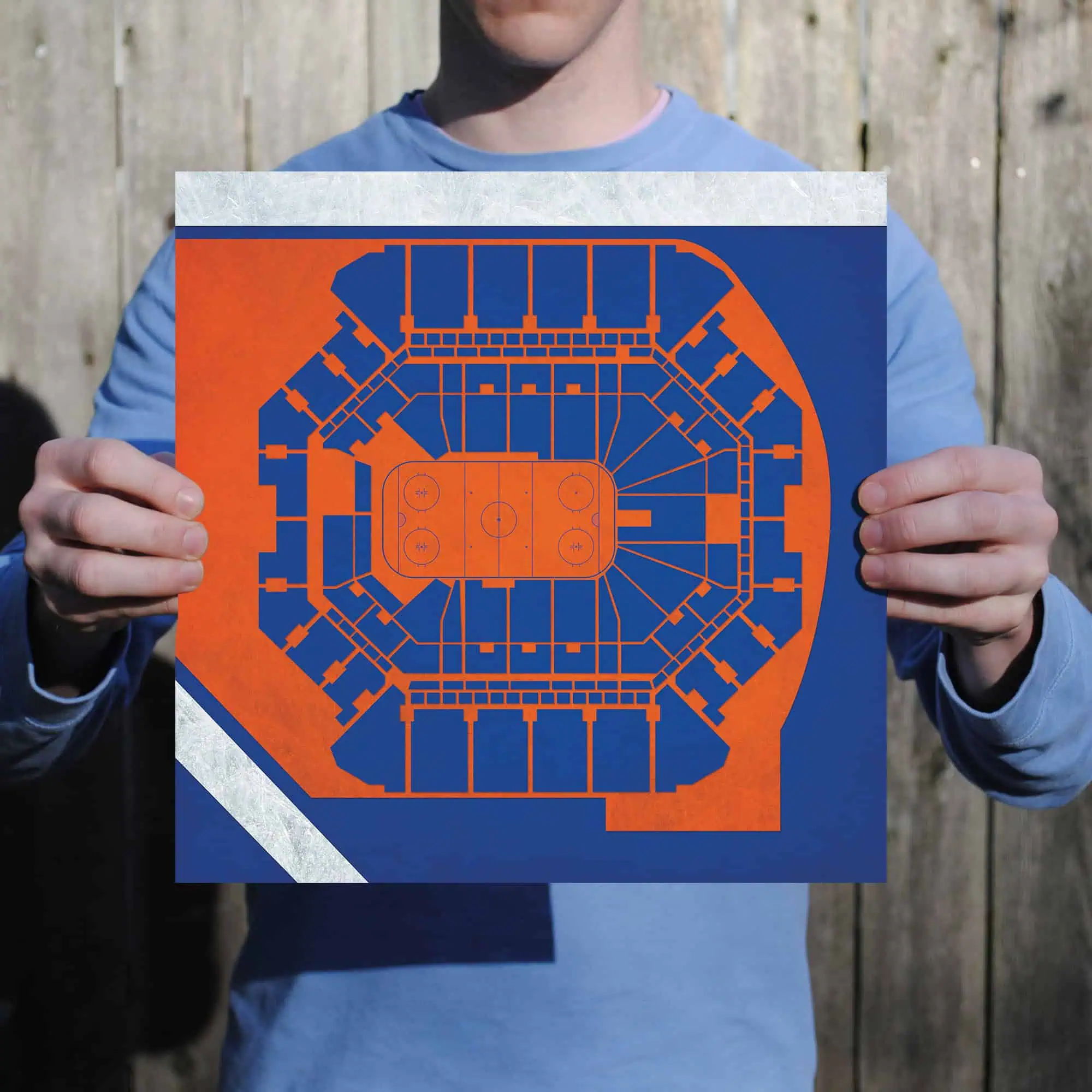 Colorful ice hockey stadium seating chart printed on a board held by a person outdoors.