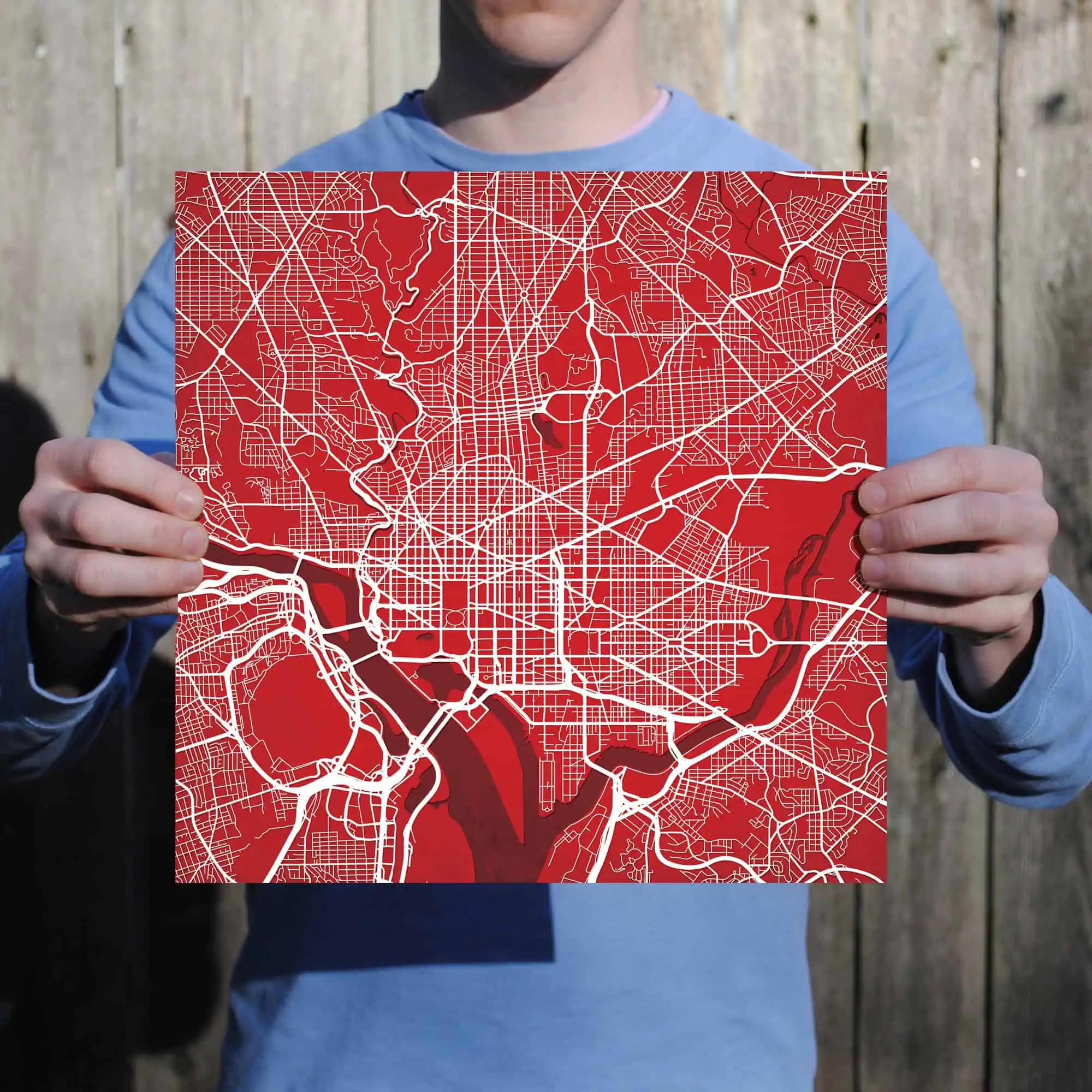 Map of a city with detailed street layout and waterways, held by a person wearing a blue jacket. The map likely represents urban navigation or geographical data for travelers and explorers.
