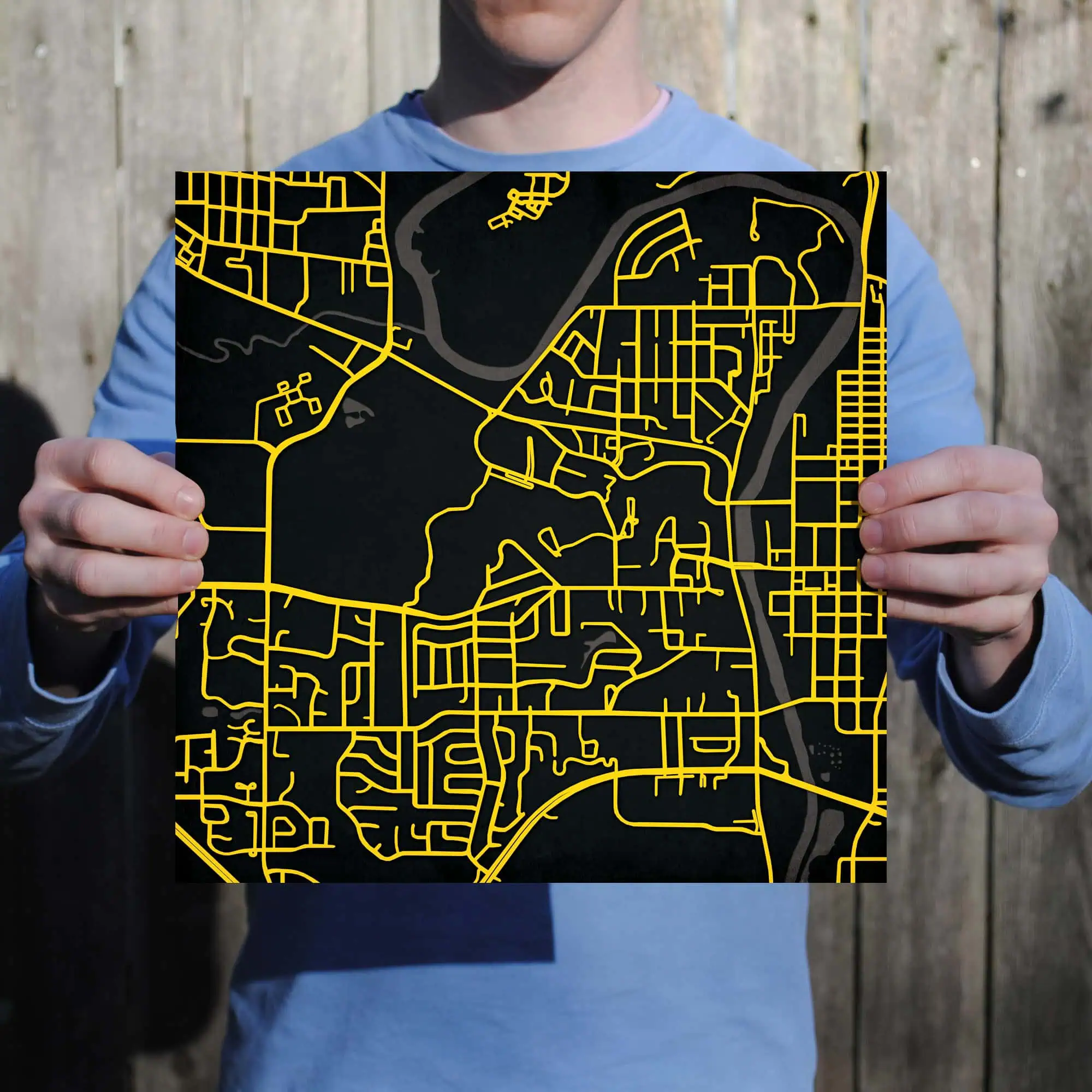 Detailed city street map with yellow roads on a black background, held by a person outdoors, ideal for navigation and travel planning.