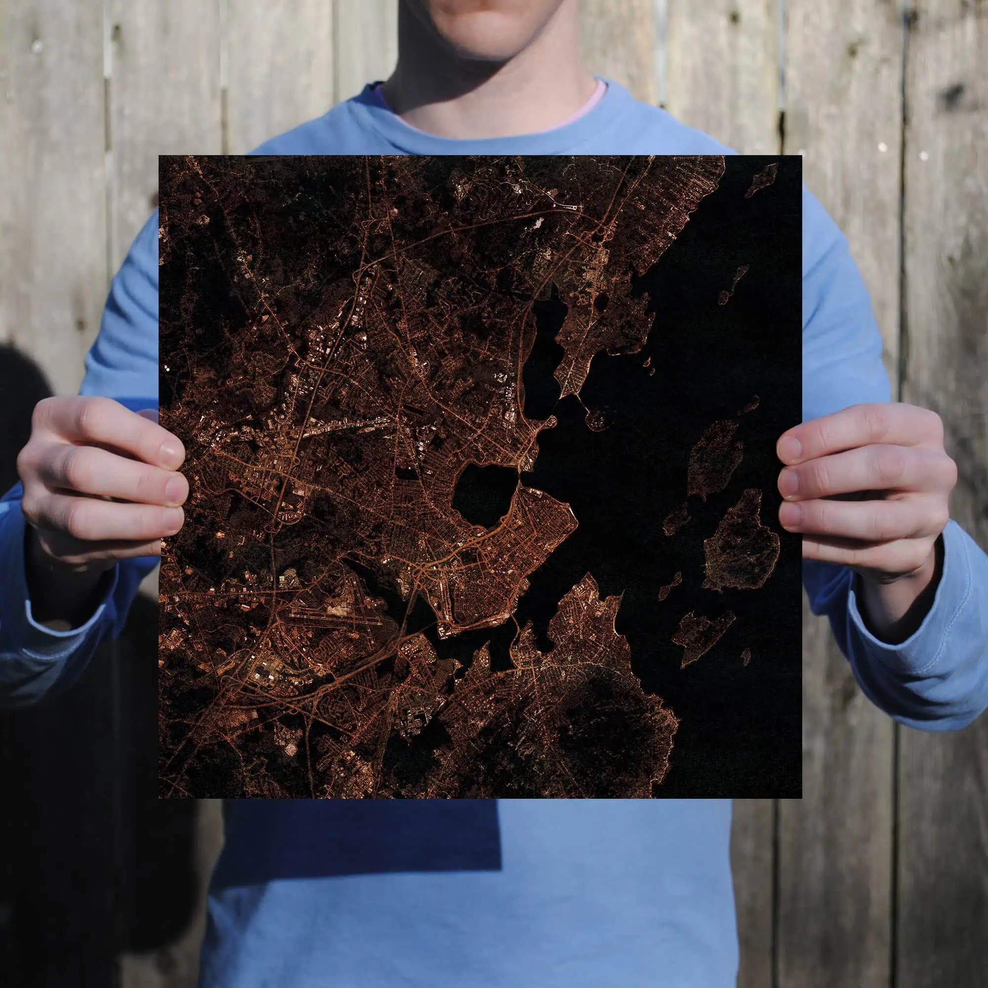 A person holding a detailed map of a city at night, showing streets and water bodies illuminated in warm tones. Perfect for outdoor navigation, maps, and geographic exploration.
