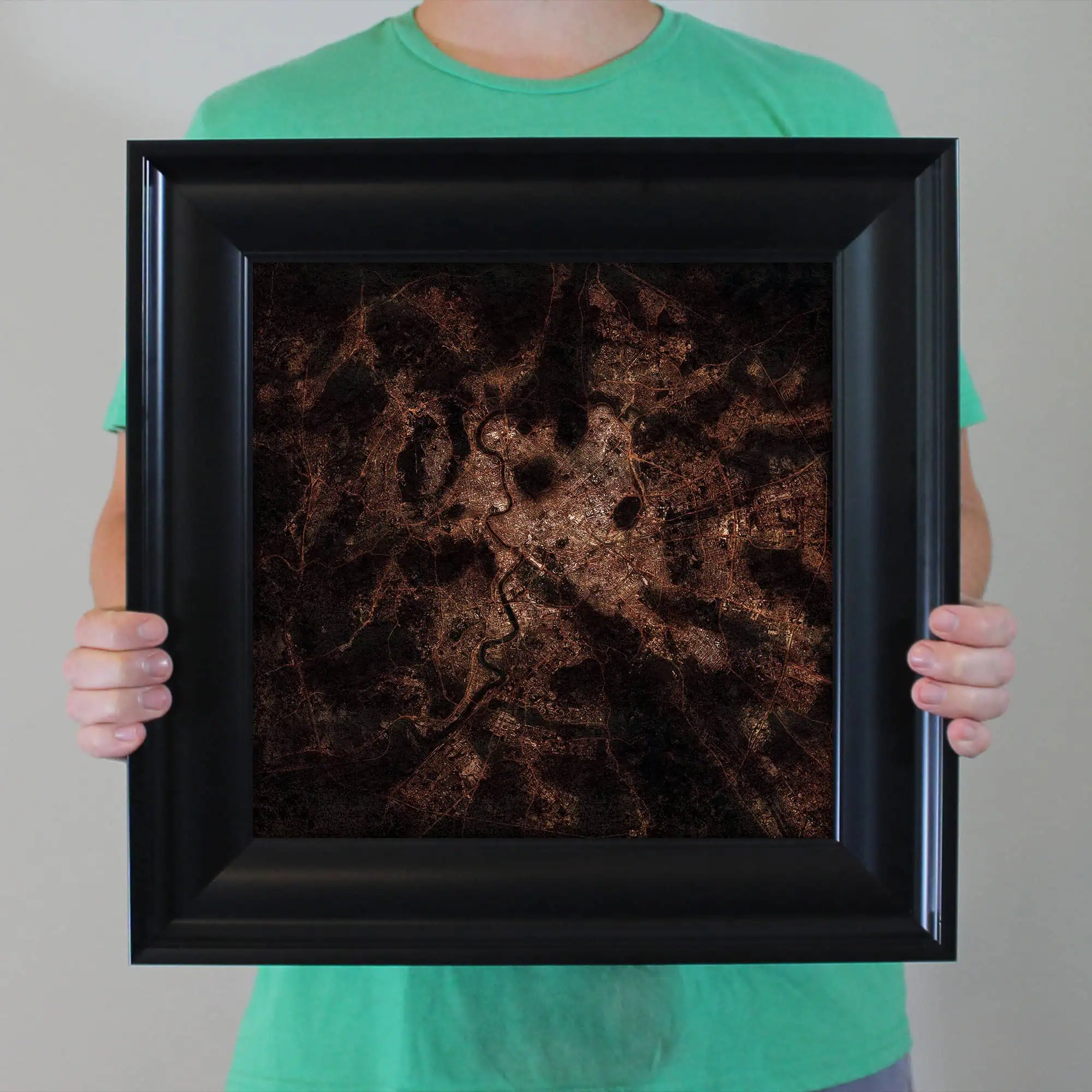 Aerial nighttime map of a city with illuminated roads and waterways, showcased in a black frame for wall display or decor, emphasizing urban layout and infrastructure.