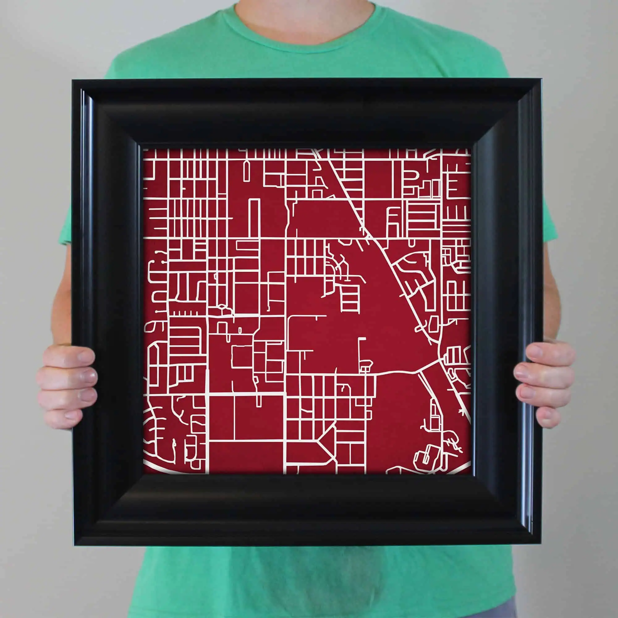 Detailed map of a city with streets and blocks, printed on a red background, framed for display or decoration. Ideal for travel, navigation, and geographic reference.