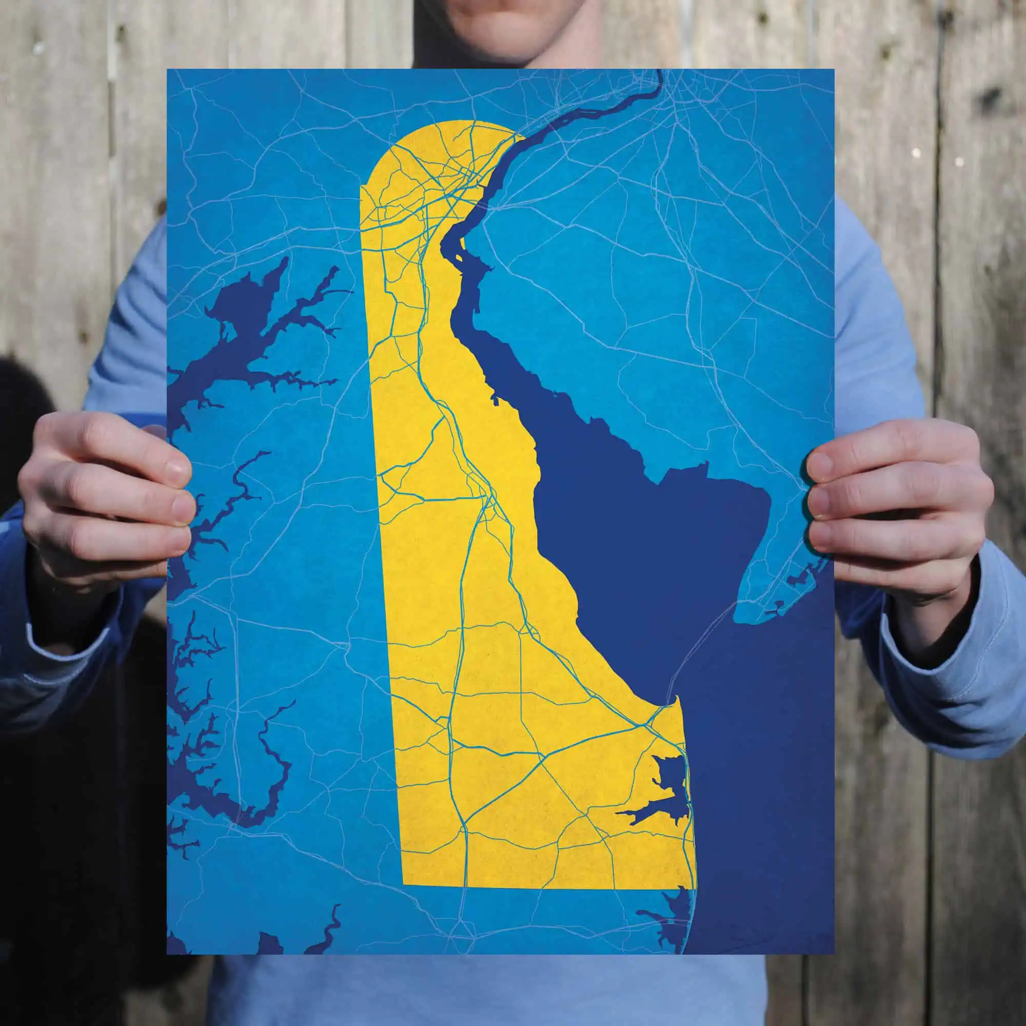 Detailed map of Maryland with major roads and waterways, held by a person in front of a wooden background. Perfect for exploring Maryland travel, navigation, and geographic information.