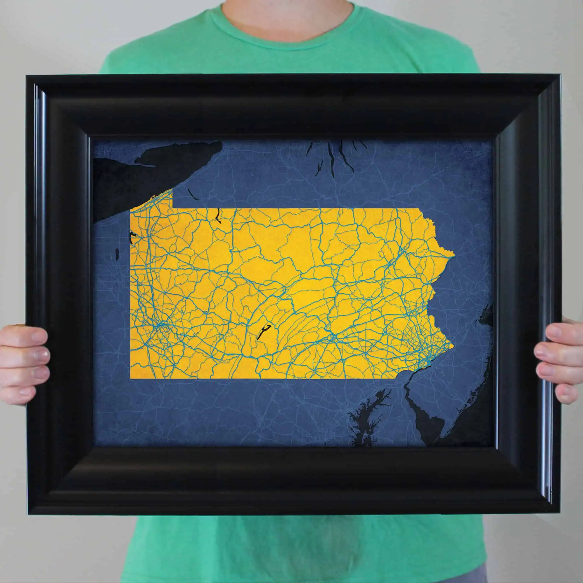 Detailed map of Pennsylvania highlighting roadways and highways, framed and held by a person in a green shirt for display or travel planning purposes.
