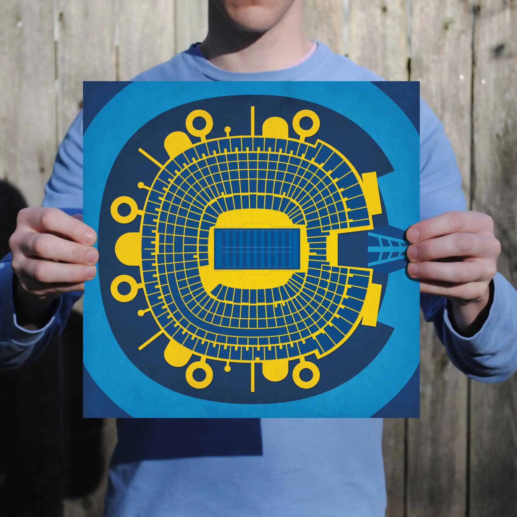 Futuristic stadium seating diagram print held by a person outdoors in front of a wooden fence.