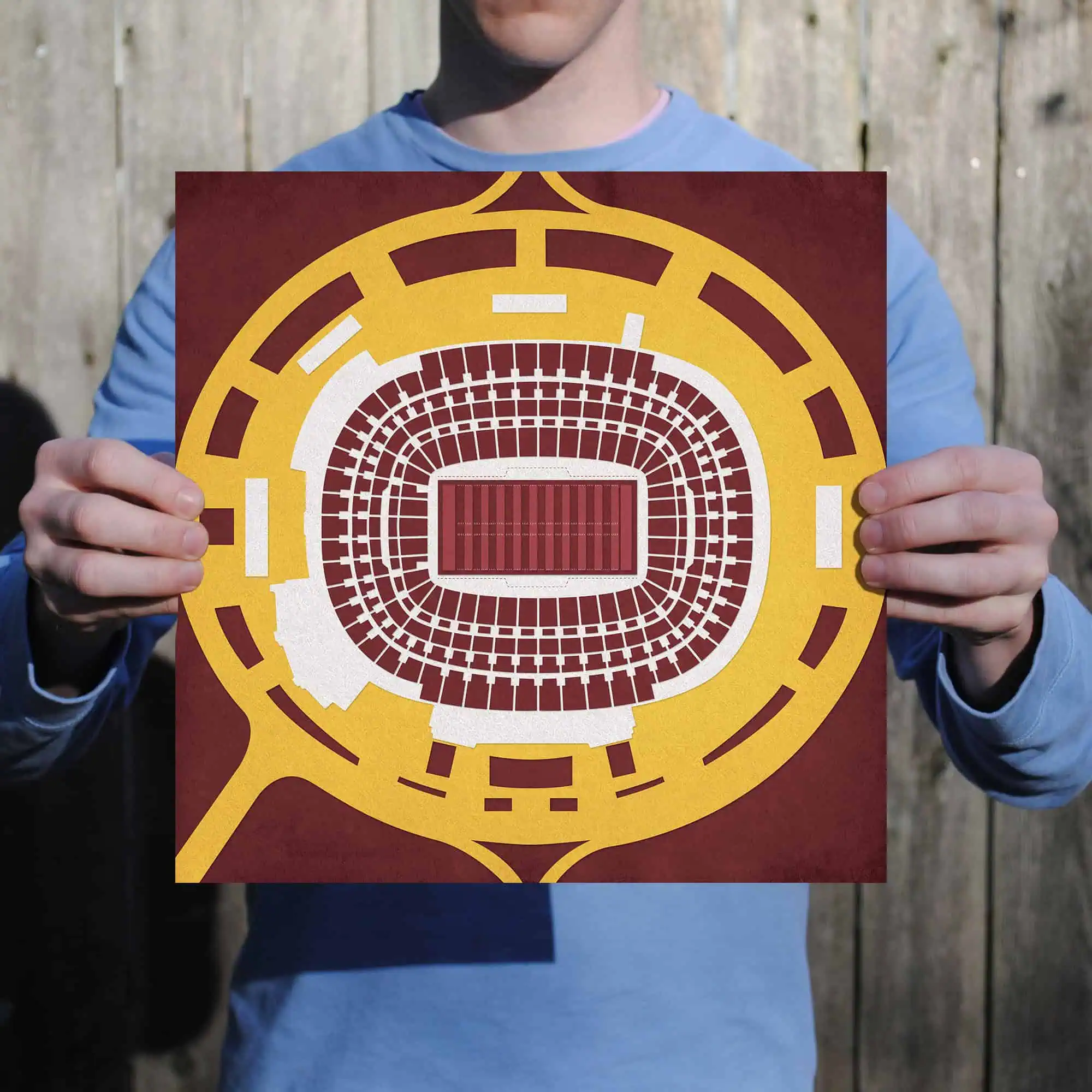 A person holding a stadium seating chart showing a detailed layout of an arena with a football field at the center, ideal for sports enthusiasts and event planning.
