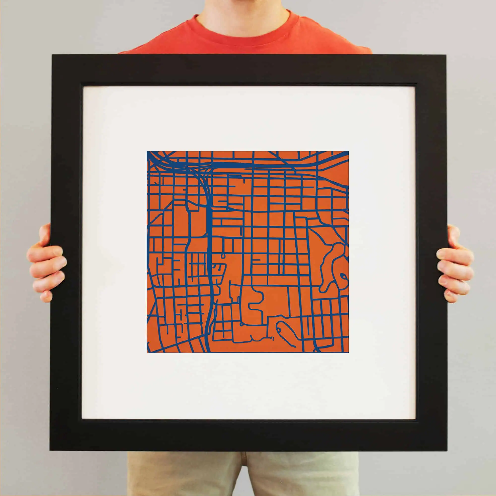 Colorful map artwork featuring a stylized city grid with orange background and blue lines, framed for wall decor and map enthusiasts.
