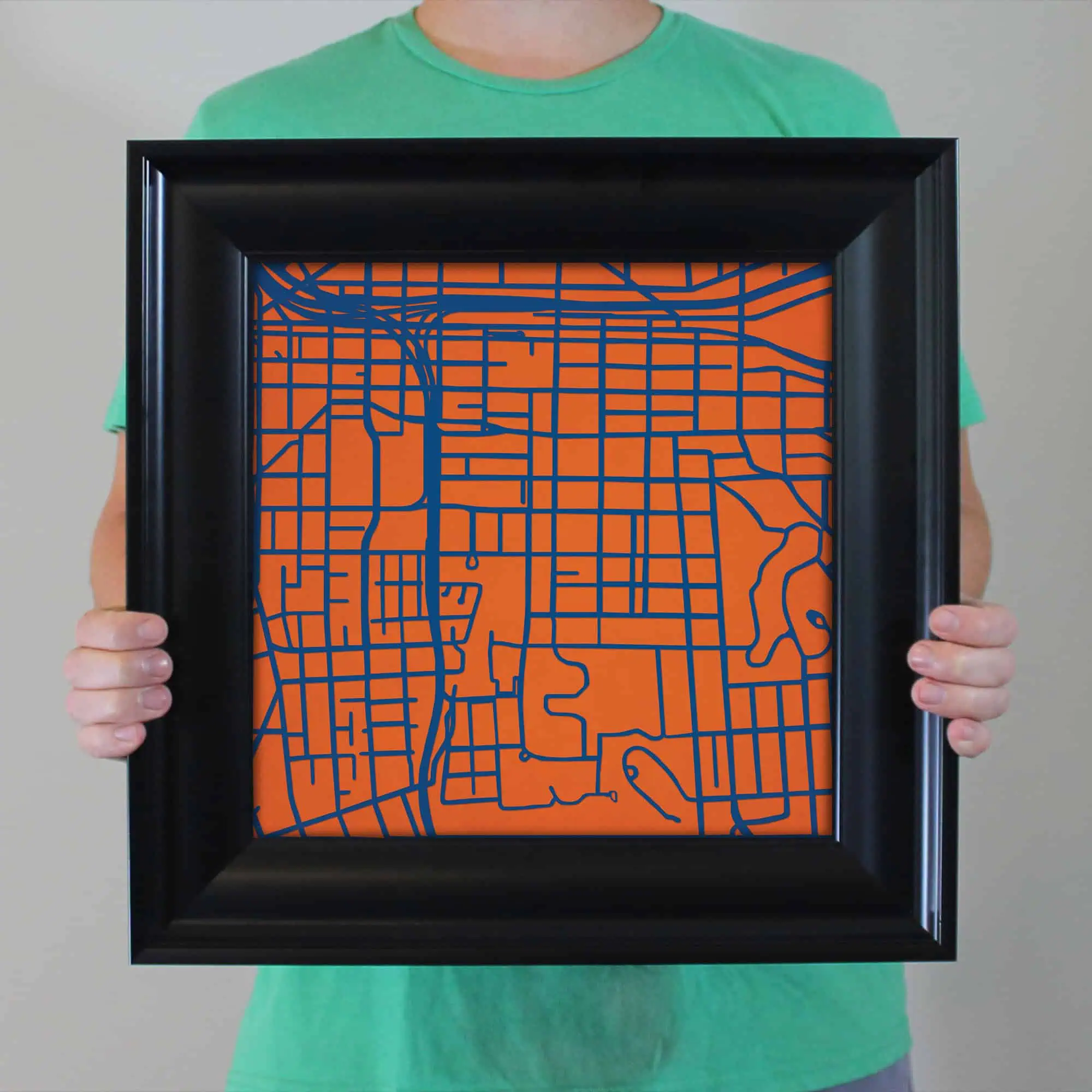 Colorful map art frame showcasing a detailed city street map in bright orange and navy blue, perfect for wall décor and travel-themed interior design.