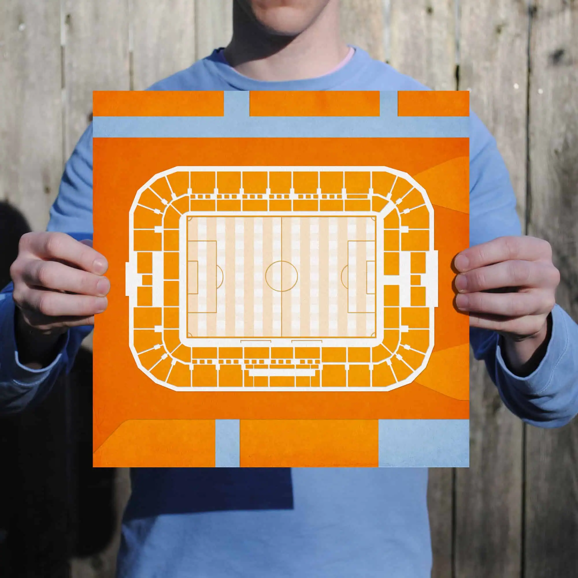 A person holding an orange and white stadium seating chart with a soccer field layout, ideal for sports events and ticketing information. Perfect for sports venue maps and ticketing services.