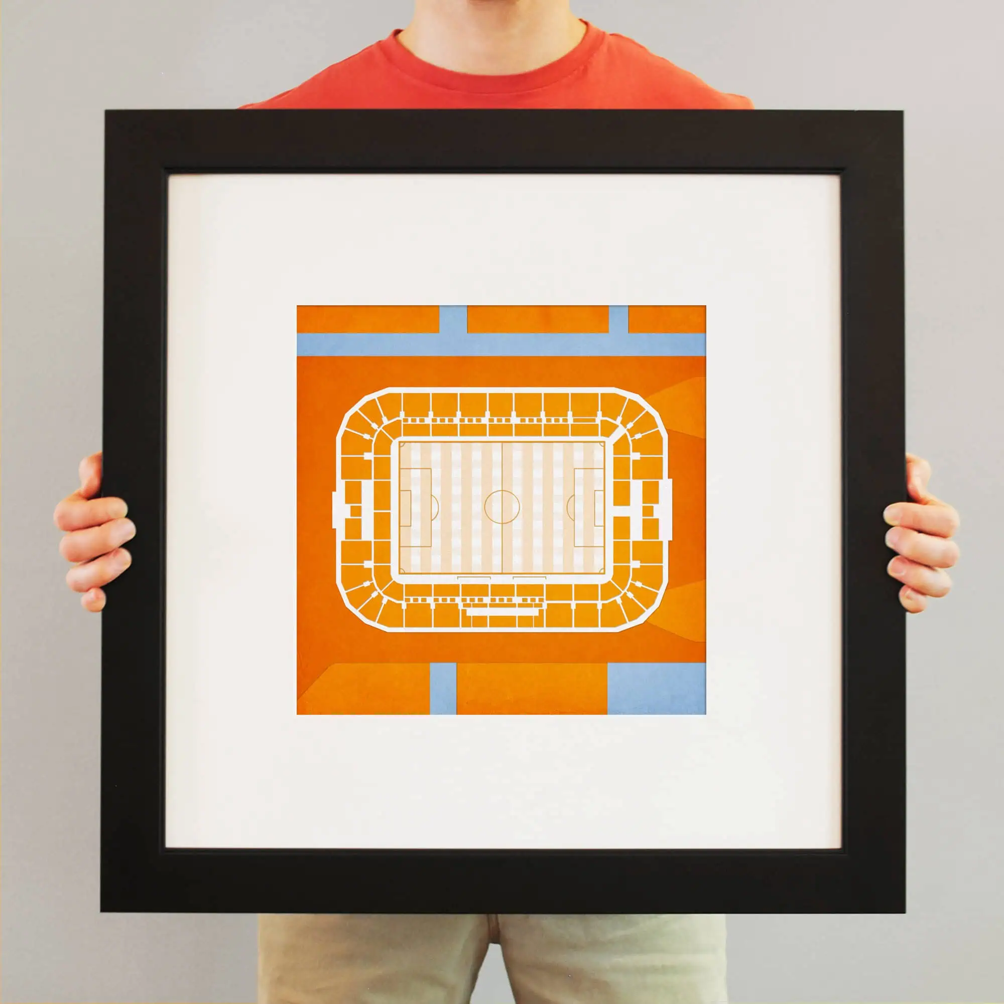Excited person holding a framed stadium seating chart artwork, perfect for sports or concert venue maps, showcasing creative interior decor ideas.