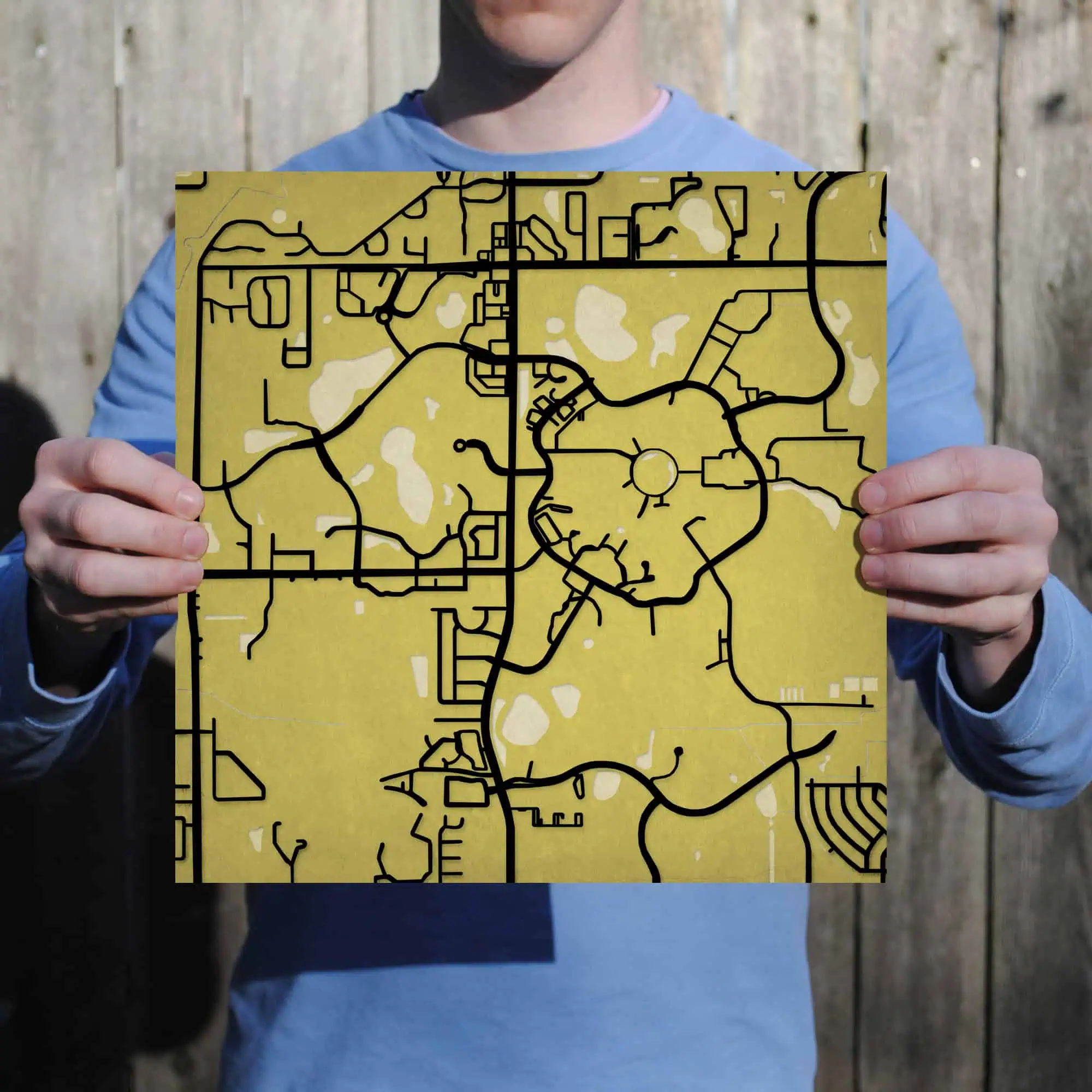 Vibrant yellow city map held by a person outdoors, showcasing detailed street layouts and pathways for navigation, ideal for travel planning and geographic reference.