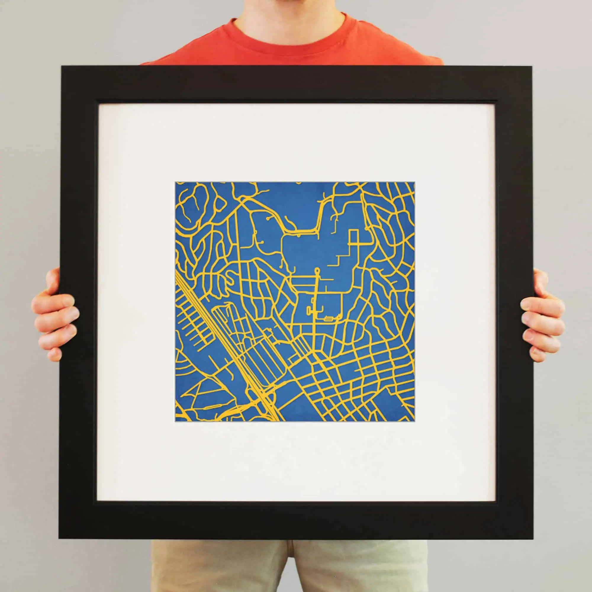 Colorful city street map artwork in a black frame, ideal for home or office decor, showcasing detailed urban street layouts with vibrant blue and yellow design elements.