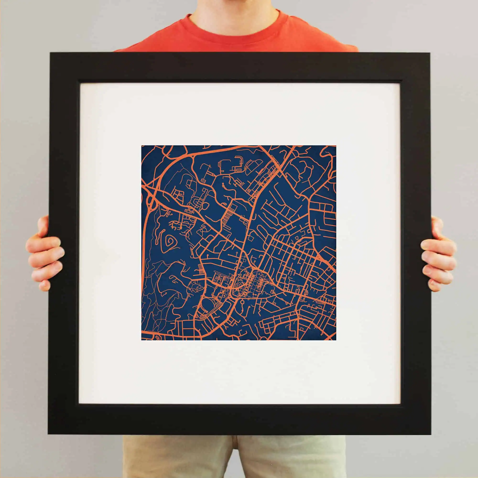 Colorful city street map artwork in a black frame, showcasing detailed urban layout with vibrant orange lines on a navy background. Perfect for home or office decor.