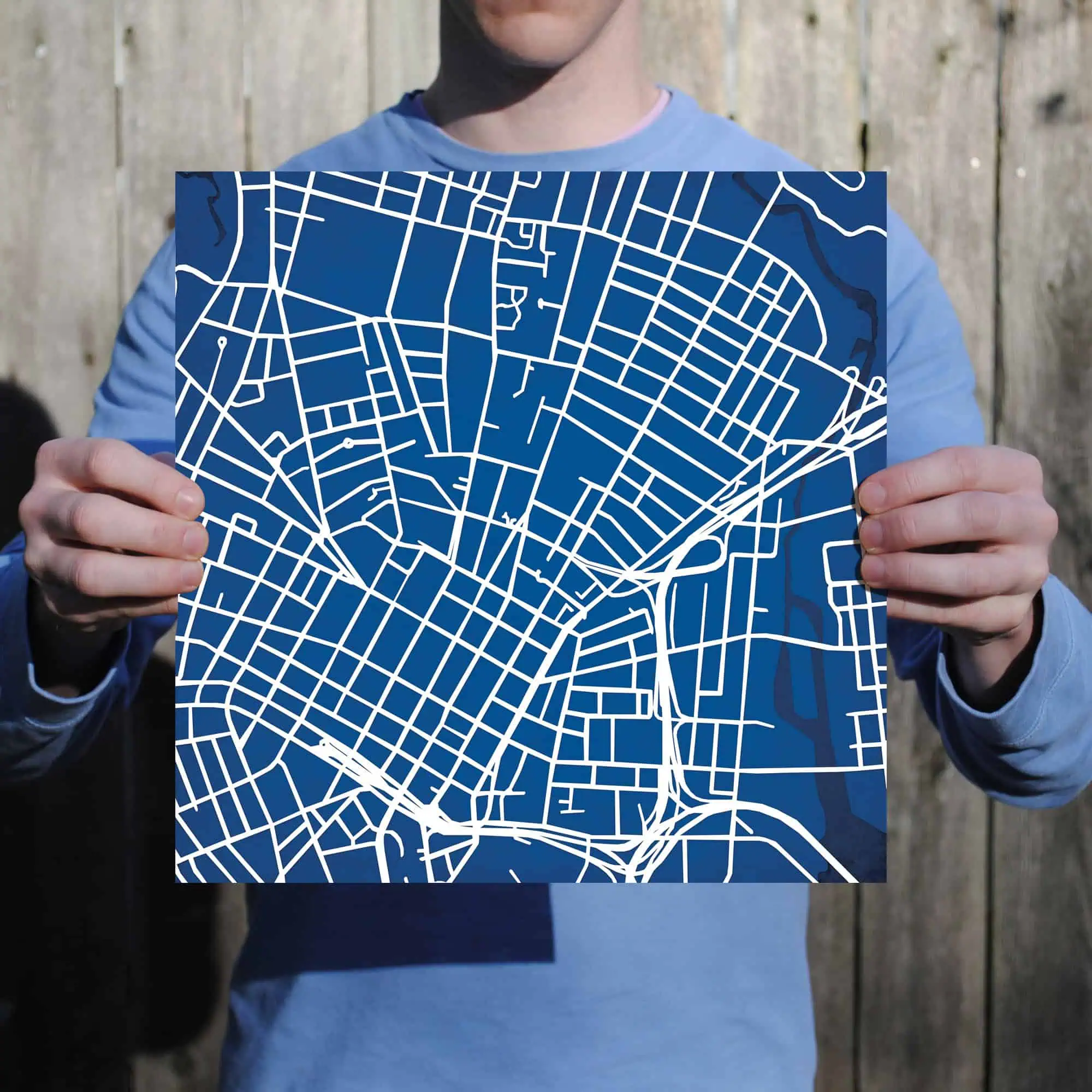 Detailed urban city street map on blue background held by person.