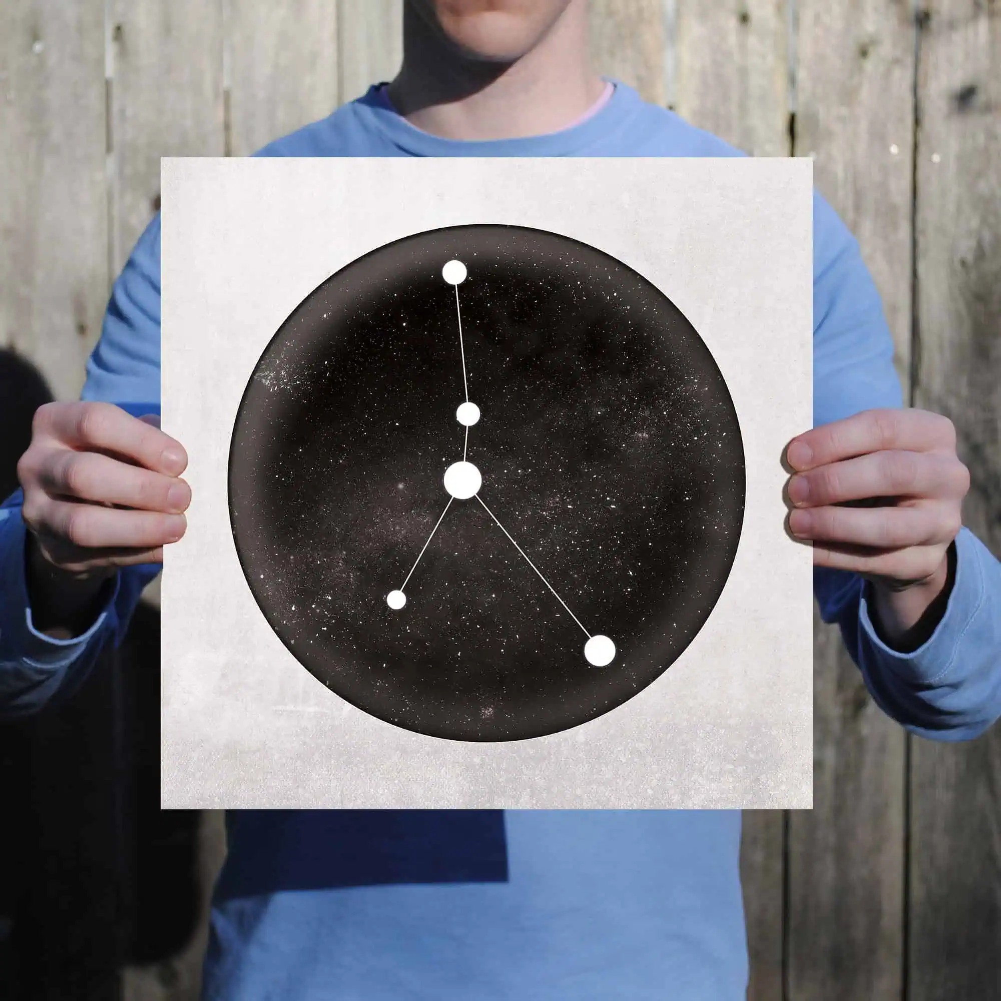 Star constellation chart with galaxy background, held by a person outdoors.